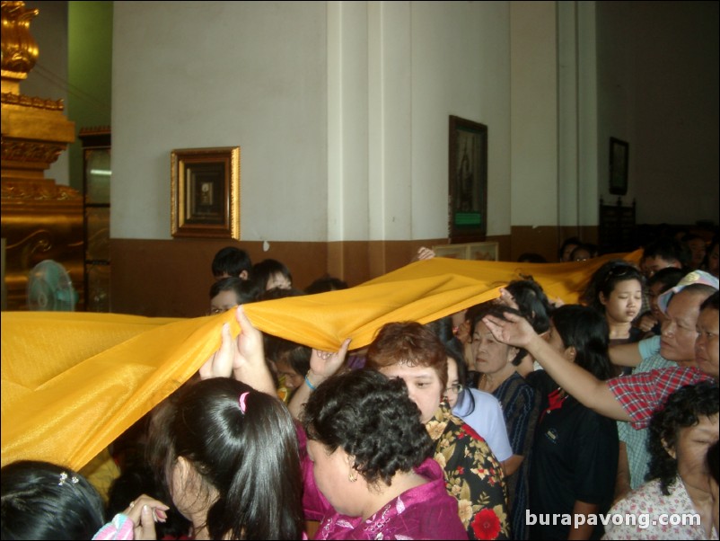 People holding up the Buddha's golden robe for good luck, Wat Phra Mongkol Bophit.