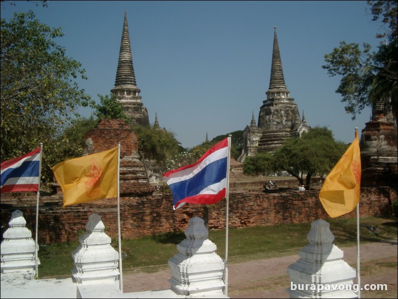 Thai national flags with Wat Phra Si Sanphet in the background.