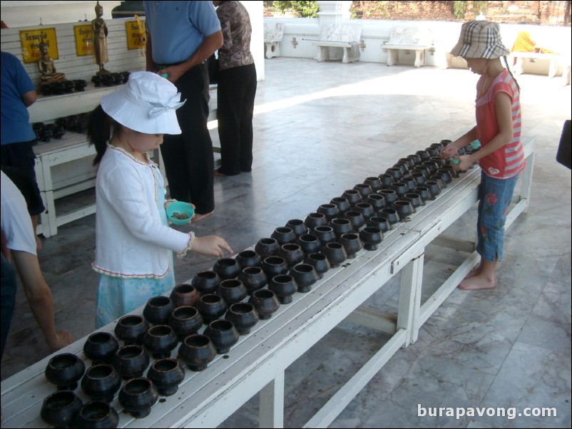 Putting coins into bowls, Wat Phra Mongkol Bophit.