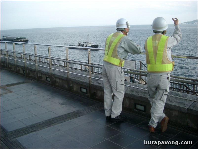 Workers looking out towards the ocean from underneath Akashi-Kaikyo Bridge.