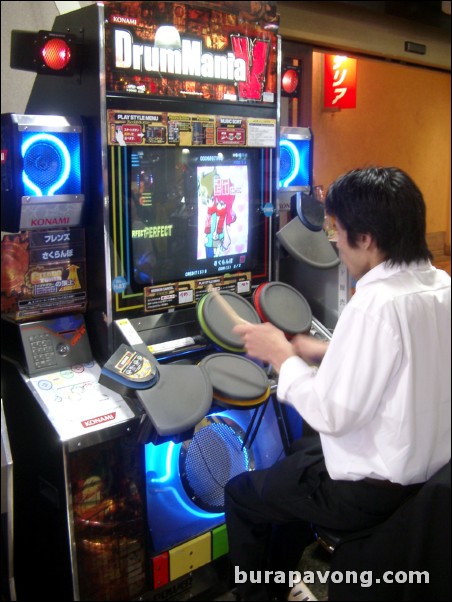 Guy playing a drum game at an arcade at Mosaic.