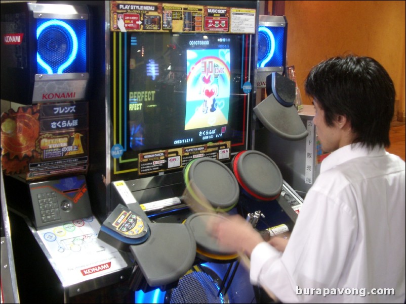 Guy playing a drum game at an arcade at Mosaic.