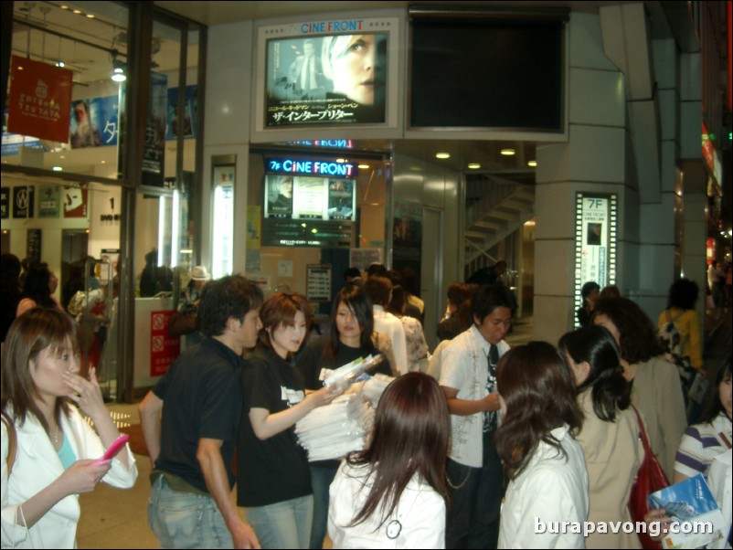 Shibuya at night. Promoters passing out Dragon Ash crush the window bags.