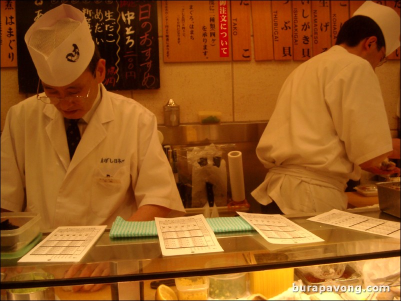 Sushi chefs inside a standing sushi bar, west Shinjuku.